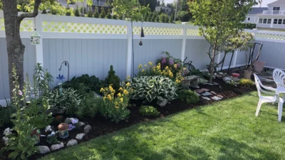 Well-maintained front yard featuring lush garden beds with colorful plantings along a residential home
